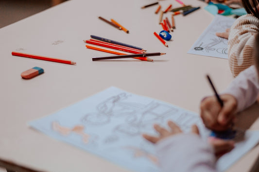 A little girl sitting at a table drawing on a piece of paper