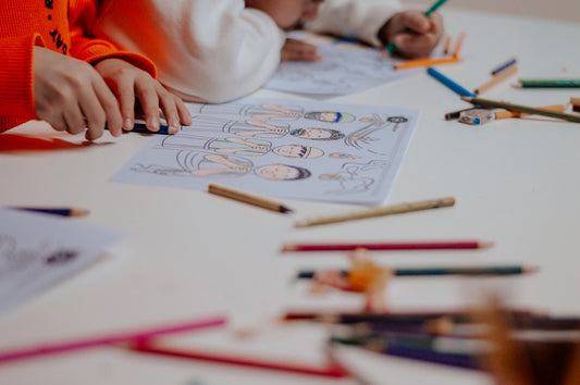 A young child sitting at a table with crayons and pencils