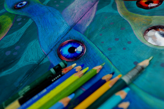 Colorful pencils arranged near a blue creature's eye